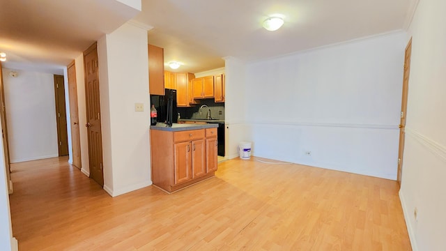 kitchen featuring decorative backsplash, black refrigerator, ornamental molding, sink, and light hardwood / wood-style flooring