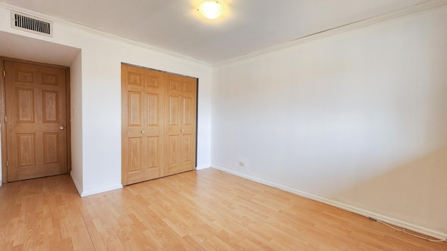 unfurnished bedroom featuring crown molding, light hardwood / wood-style flooring, and a closet