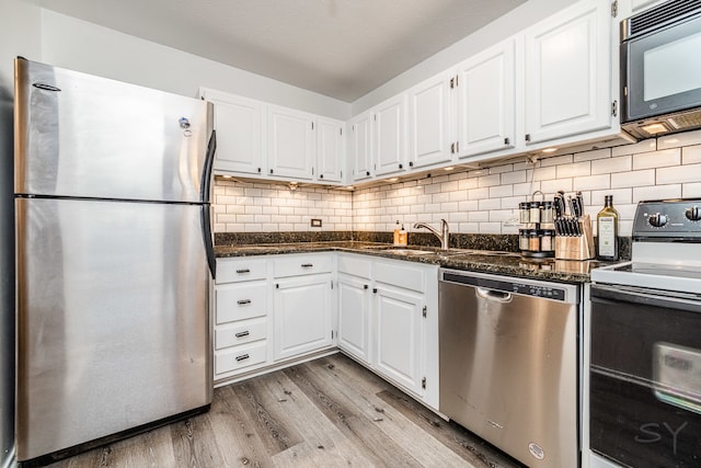 kitchen with white cabinetry, light hardwood / wood-style floors, sink, stainless steel appliances, and tasteful backsplash