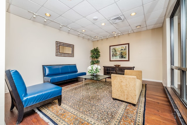 living room featuring dark hardwood / wood-style floors, a paneled ceiling, and rail lighting