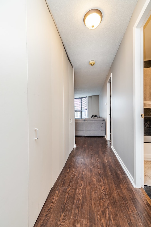 corridor with dark hardwood / wood-style flooring and a textured ceiling