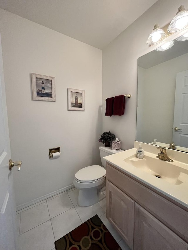 half bathroom featuring tile patterned floors, vanity, baseboards, and toilet