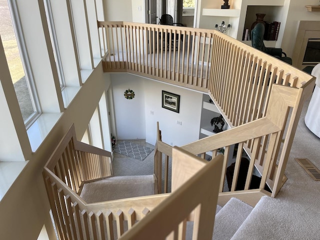 stairway with visible vents, a high ceiling, and carpet floors