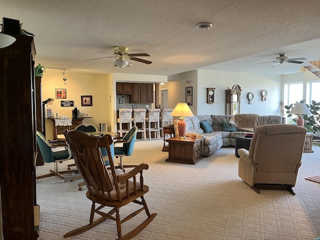 living area featuring light carpet, a textured ceiling, and ceiling fan