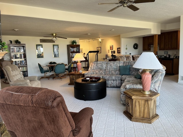 living room with light carpet, a textured ceiling, and a ceiling fan
