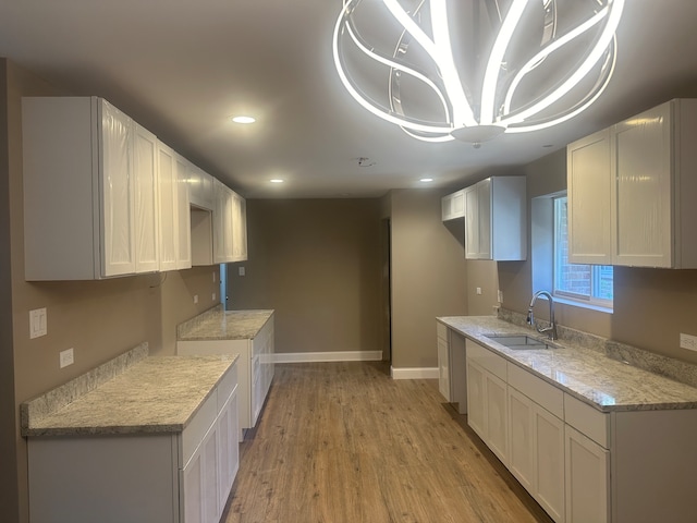 kitchen featuring white cabinetry, light wood-type flooring, and sink