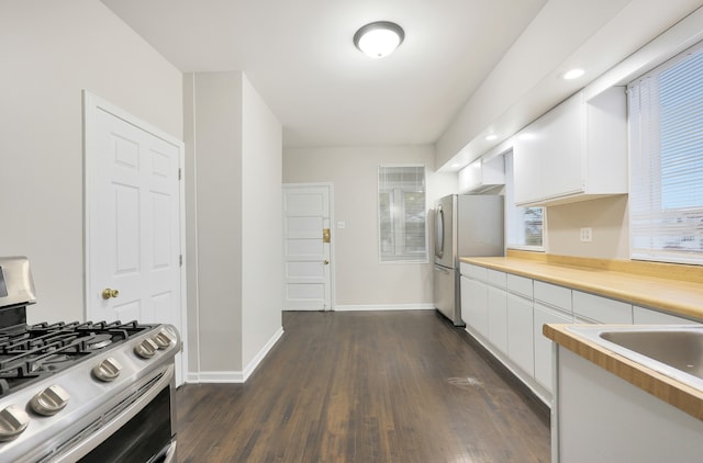 kitchen featuring range with gas stovetop, dark hardwood / wood-style floors, white cabinetry, and stainless steel refrigerator