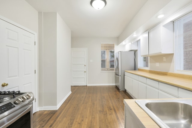 kitchen with white cabinets, appliances with stainless steel finishes, dark hardwood / wood-style floors, and sink