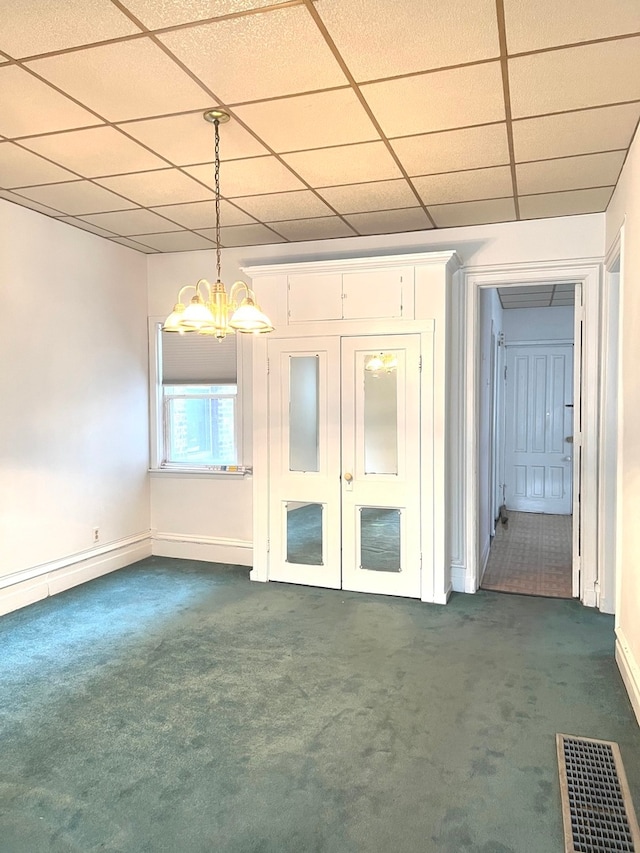 carpeted empty room featuring a paneled ceiling, a notable chandelier, and french doors