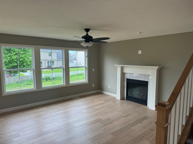 unfurnished living room featuring plenty of natural light, light hardwood / wood-style flooring, and a tiled fireplace