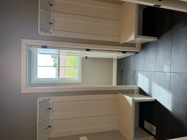 interior space with tile walls and white cabinetry