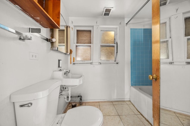 bathroom featuring toilet, tiled shower / bath combo, and tile patterned flooring