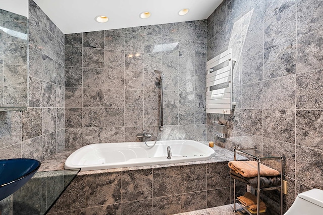 bathroom with toilet, radiator heating unit, tile walls, and tiled tub