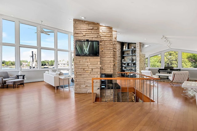 bar with a fireplace, hardwood / wood-style flooring, vaulted ceiling, and built in features