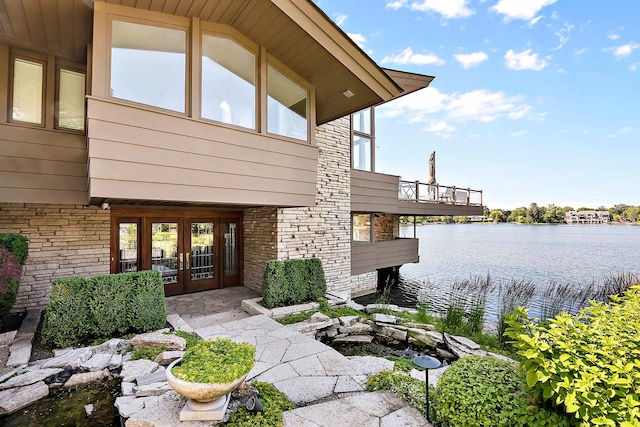 view of exterior entry featuring french doors and a water view