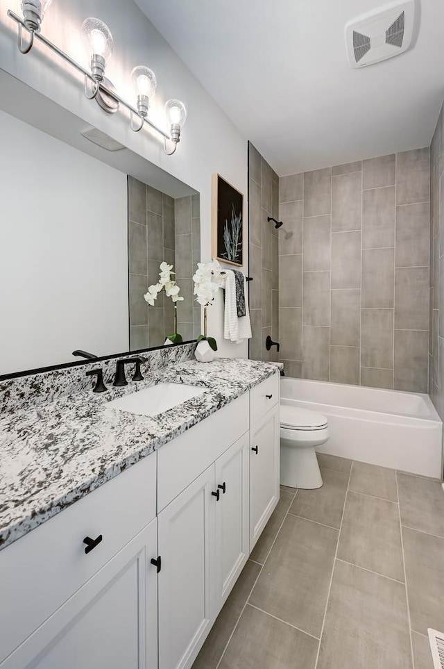 full bathroom featuring vanity, tiled shower / bath combo, tile patterned floors, and toilet