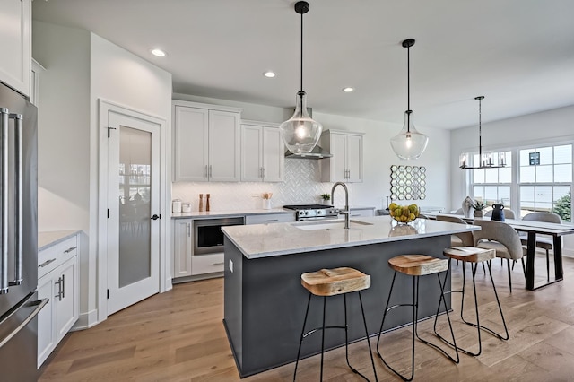 kitchen featuring white cabinetry, appliances with stainless steel finishes, an island with sink, and light wood-type flooring