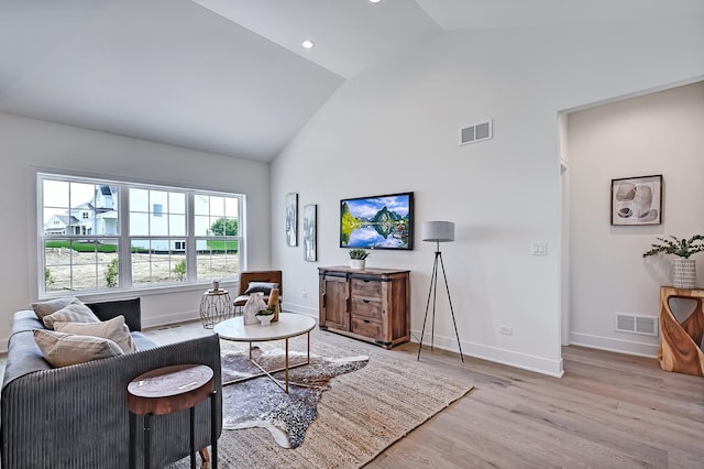 living room with high vaulted ceiling and light hardwood / wood-style floors