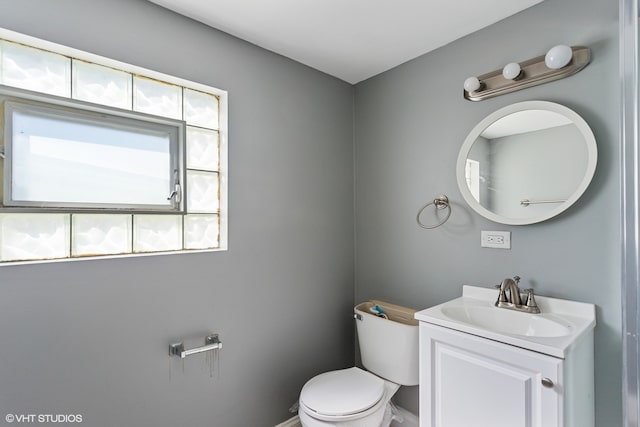 bathroom with toilet, vanity, and a wealth of natural light