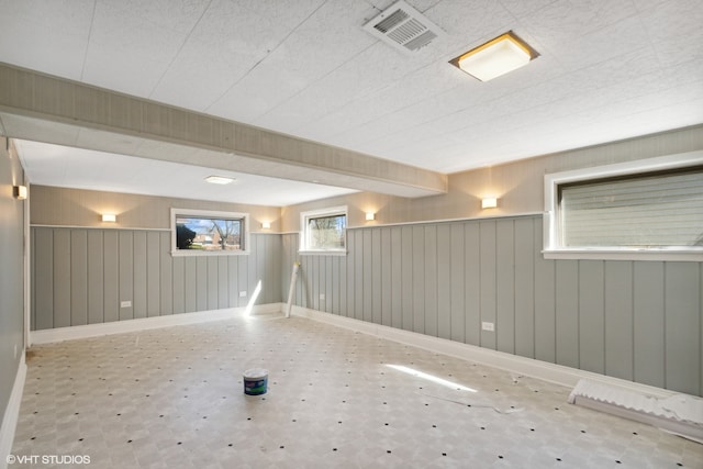 basement featuring wooden walls and light tile floors