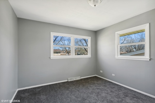 spare room featuring dark colored carpet