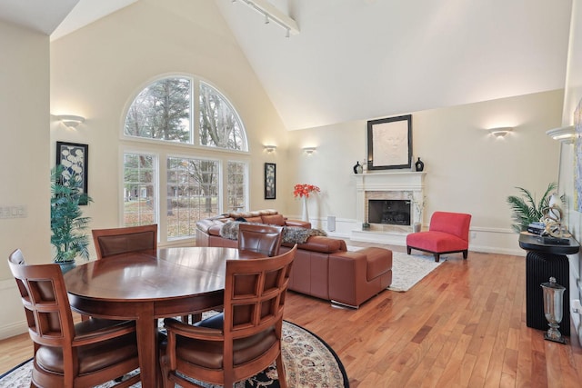 dining area featuring rail lighting, high vaulted ceiling, and light hardwood / wood-style flooring