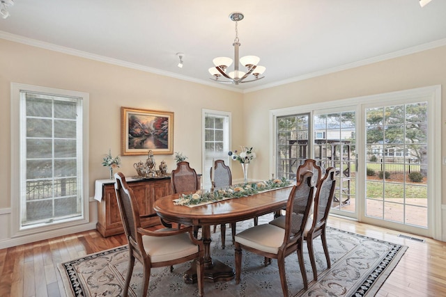 dining room with crown molding, light wood-type flooring, and a chandelier