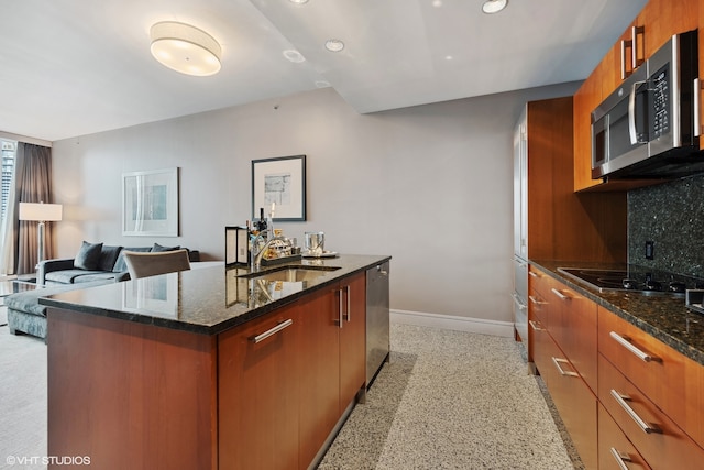 kitchen with appliances with stainless steel finishes, sink, dark stone counters, and tasteful backsplash