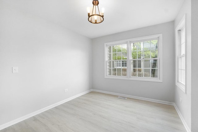 unfurnished room with light hardwood / wood-style flooring and a notable chandelier