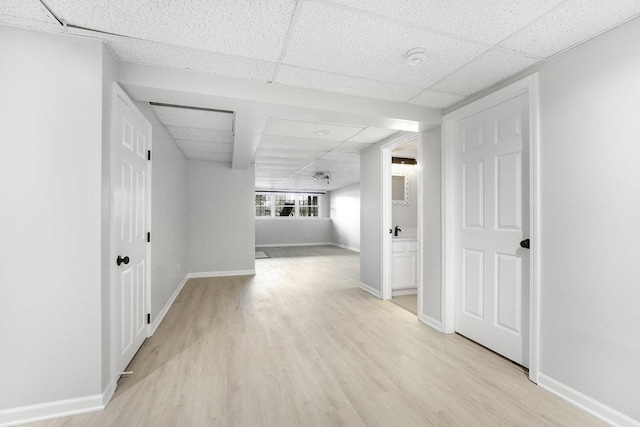 hall with a drop ceiling and light wood-type flooring