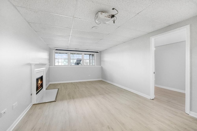 unfurnished living room with a drop ceiling and light hardwood / wood-style flooring