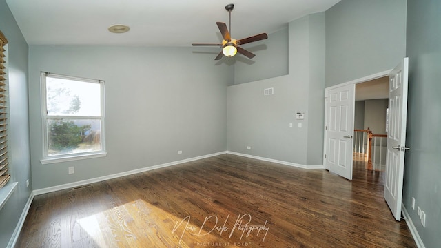 empty room featuring ceiling fan, dark hardwood / wood-style floors, and a high ceiling