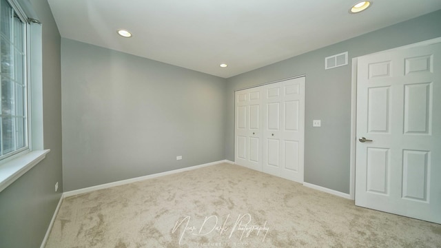 unfurnished bedroom featuring light colored carpet and a closet