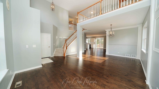 unfurnished living room with dark hardwood / wood-style flooring, a chandelier, and a high ceiling