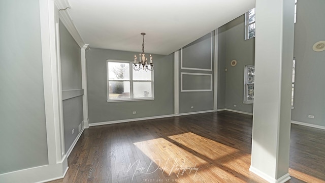 unfurnished dining area featuring a notable chandelier, dark wood-type flooring, and decorative columns