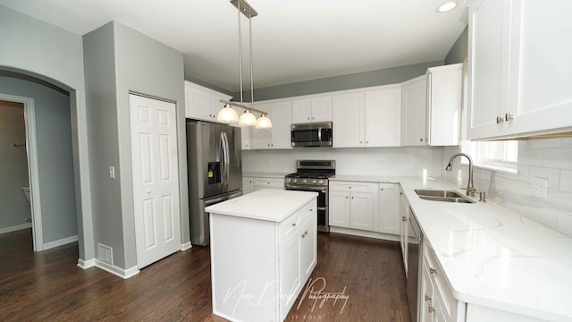 kitchen featuring a kitchen island, appliances with stainless steel finishes, decorative light fixtures, white cabinetry, and sink