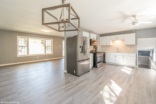 kitchen featuring appliances with stainless steel finishes, sink, white cabinetry, light hardwood / wood-style floors, and decorative backsplash