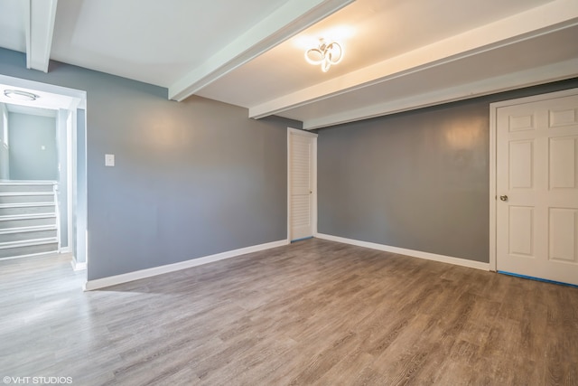 spare room featuring beam ceiling and wood-type flooring