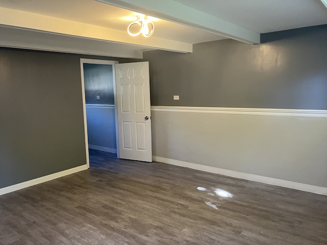 spare room featuring beam ceiling and dark hardwood / wood-style floors