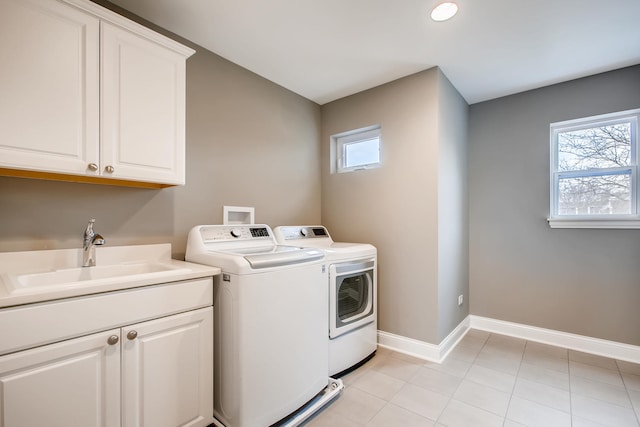 washroom featuring washing machine and clothes dryer, sink, cabinets, and a wealth of natural light