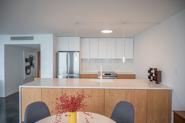 kitchen with stainless steel appliances, backsplash, white cabinetry, and light stone counters