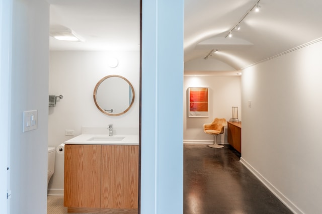 corridor with lofted ceiling, sink, and track lighting