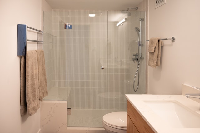 bathroom with toilet, tiled shower, and vanity