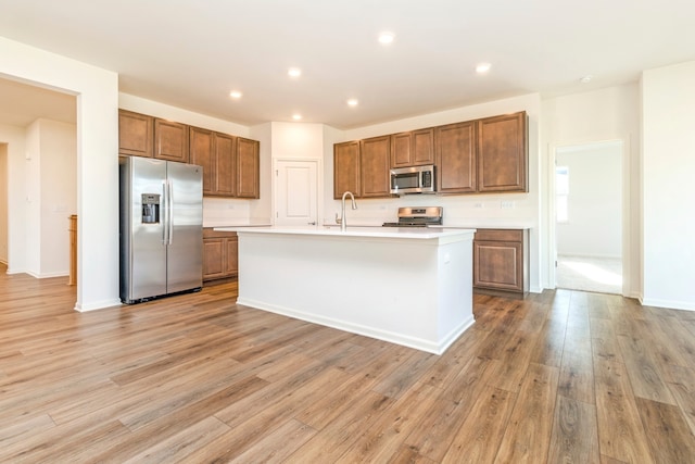 kitchen with a center island with sink, light hardwood / wood-style floors, and stainless steel appliances