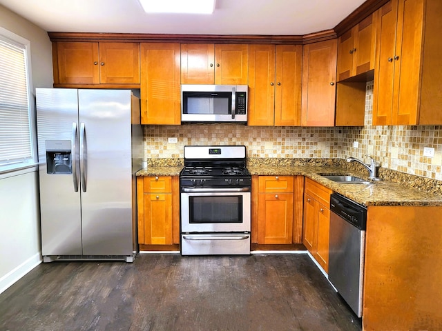 kitchen with dark hardwood / wood-style floors, sink, dark stone countertops, backsplash, and stainless steel appliances