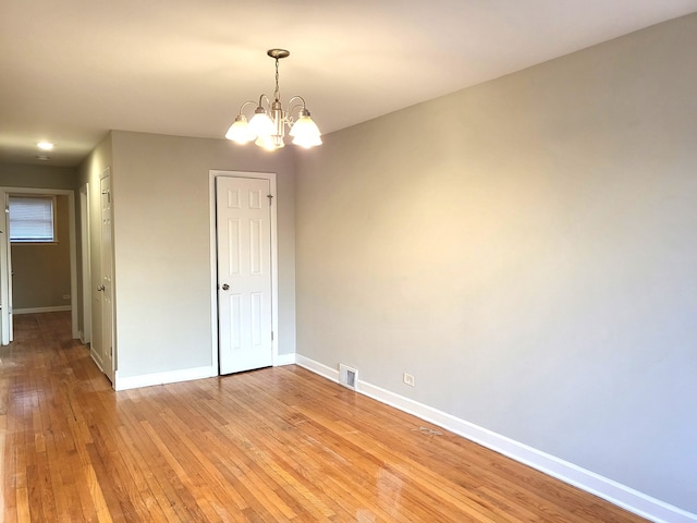 spare room featuring light hardwood / wood-style flooring and a notable chandelier