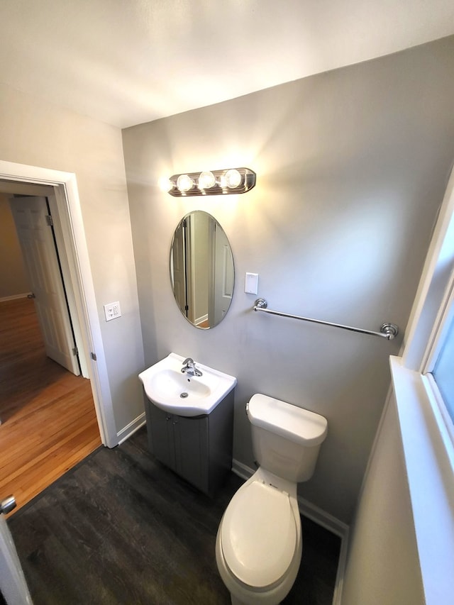 bathroom with toilet, vanity, and wood-type flooring