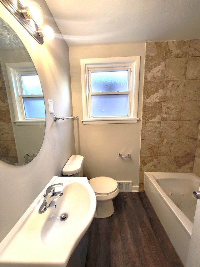 full bathroom featuring shower / washtub combination, toilet, a healthy amount of sunlight, and hardwood / wood-style floors