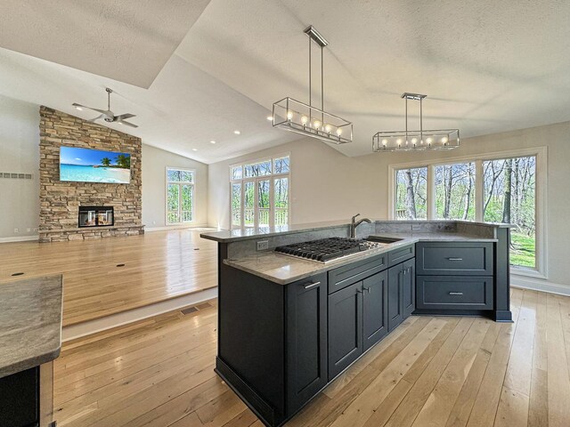 kitchen featuring a fireplace, vaulted ceiling, a healthy amount of sunlight, and light wood-type flooring