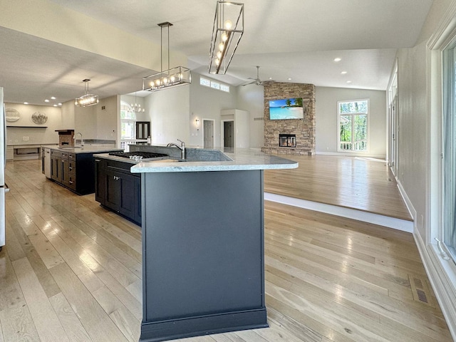 kitchen with a spacious island, a fireplace, vaulted ceiling, and pendant lighting